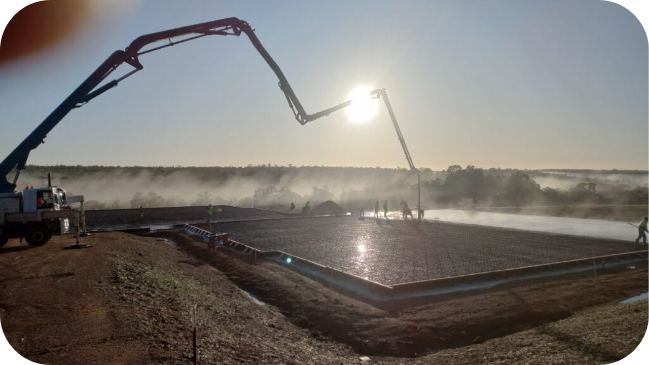 Two boom pumps are pouring concrete at sunrise while workers guide the slab, highlighting safe and coordinated pumping practices on Melbourne worksite