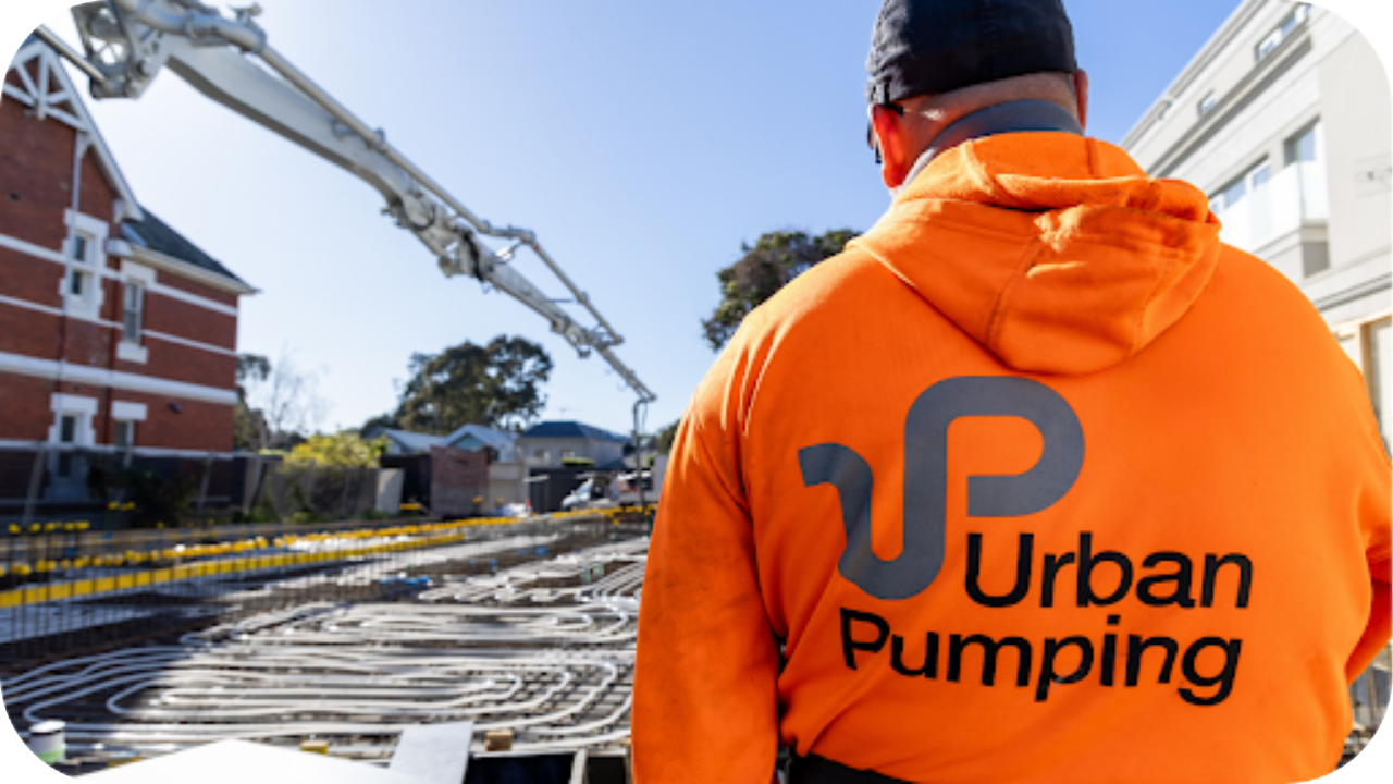 Worker in high visibility Urban Pumping gear supervising concrete pumping on a residential site, emphasising PPE and safety compliance for pumping crews
