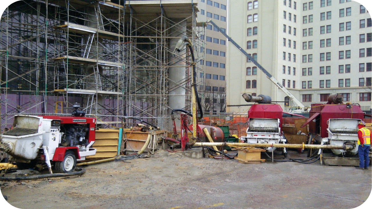 Concrete pumps feeding delivery lines at a busy high-rise site, with scaffolding and formwork crews preparing for tower boom concrete placement.