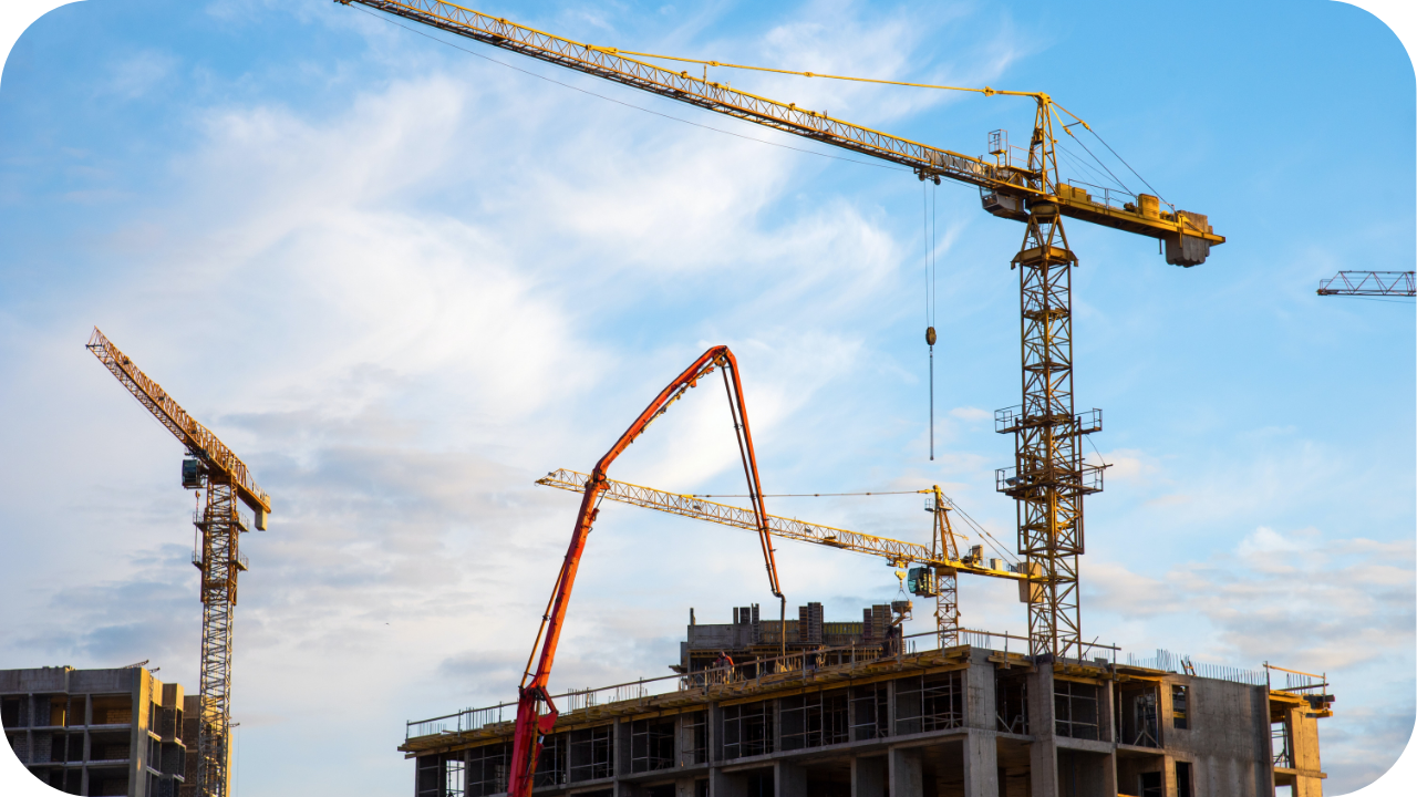 Tower boom and construction cranes working together on a multi-level building, supporting safe concrete placement across an active high-rise project.