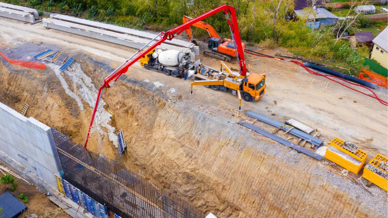 Concrete pump operating on a deep excavation with crew and machinery completing safety checks and controlled concrete placement on a Melbourne work site.
