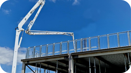 Large boom pump positioned above a multi-level structure placing concrete accurately for complex construction work under a clear Melbourne sky.