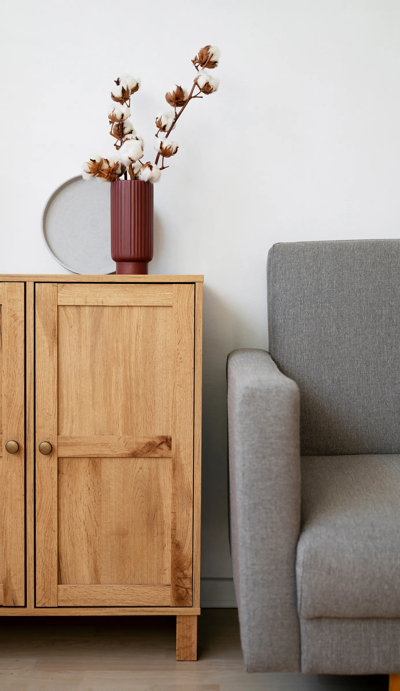 A wooden cabinet sitting next to a gray chair.