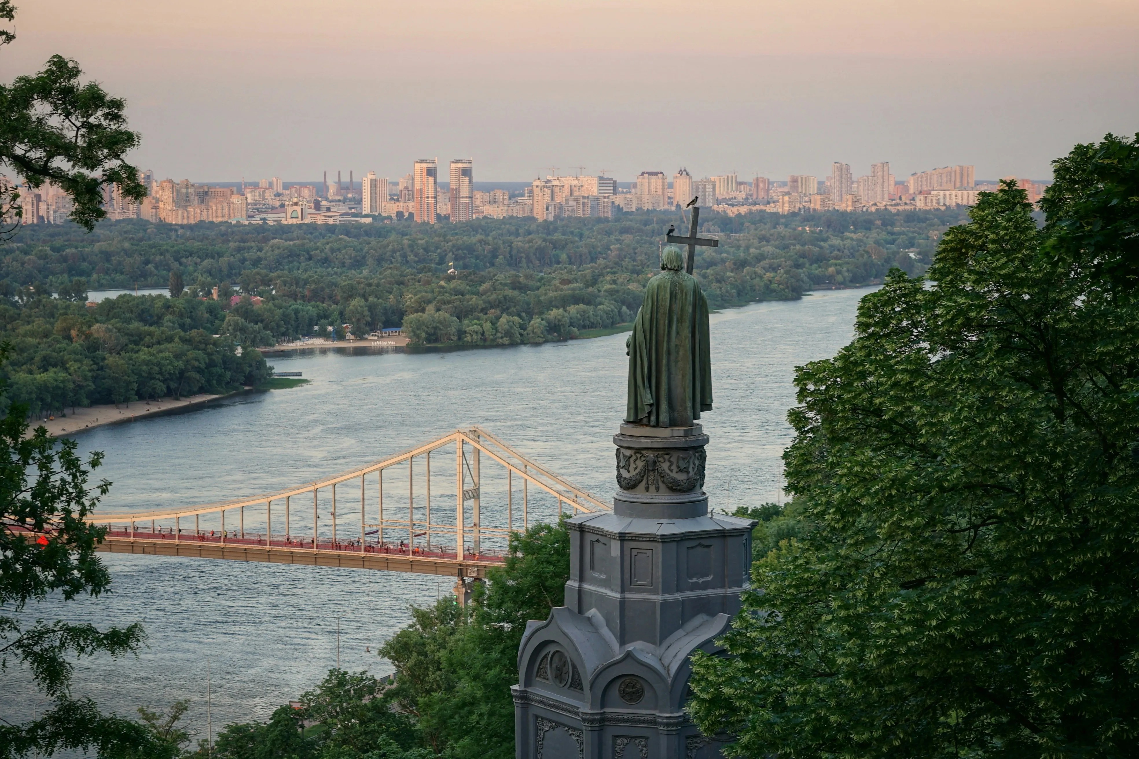 A statue on top of a tower overlooking a river.