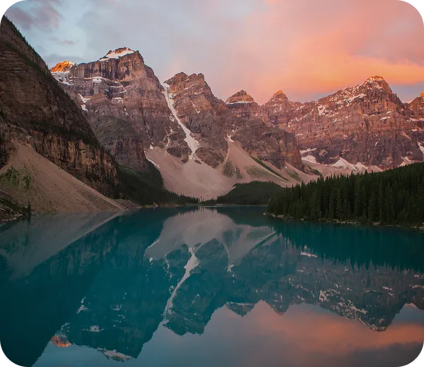 A lake surrounded by mountains and trees under a cloudy sky.