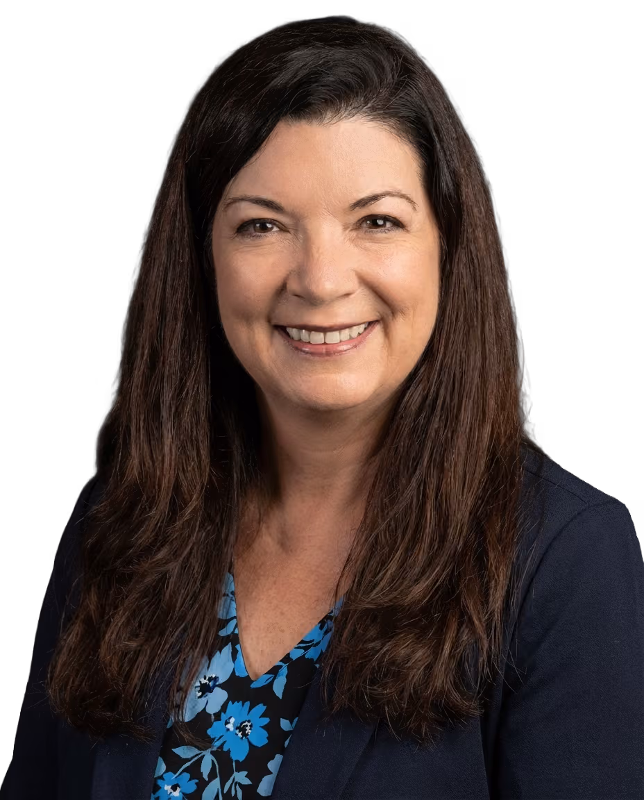 Smiling female audiologist with long brown hair wearing a navy blazer and a blue floral blouse against a black background.