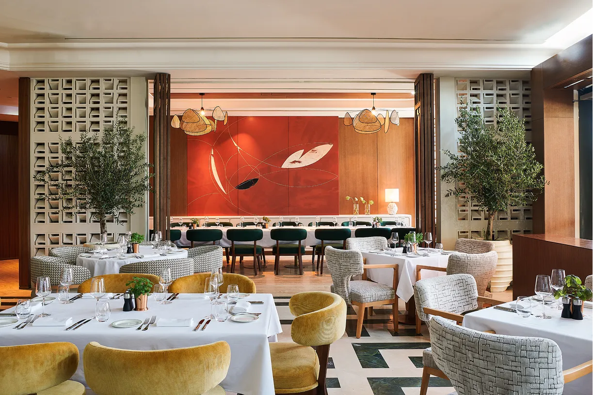 Elegant interior of Novikov Abu Dhabi featuring contemporary dining tables, velvet chairs, and modern wall art