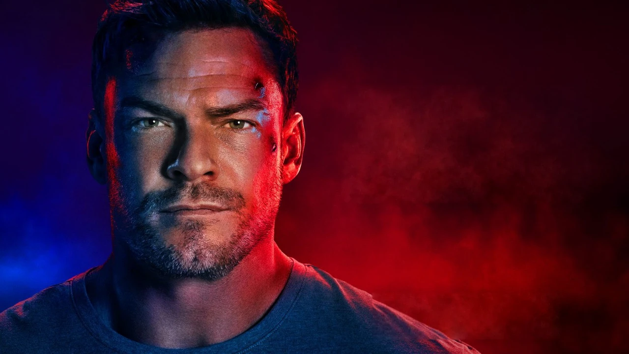 Alan Ritchson som Reacher i rødt og blåt lys.