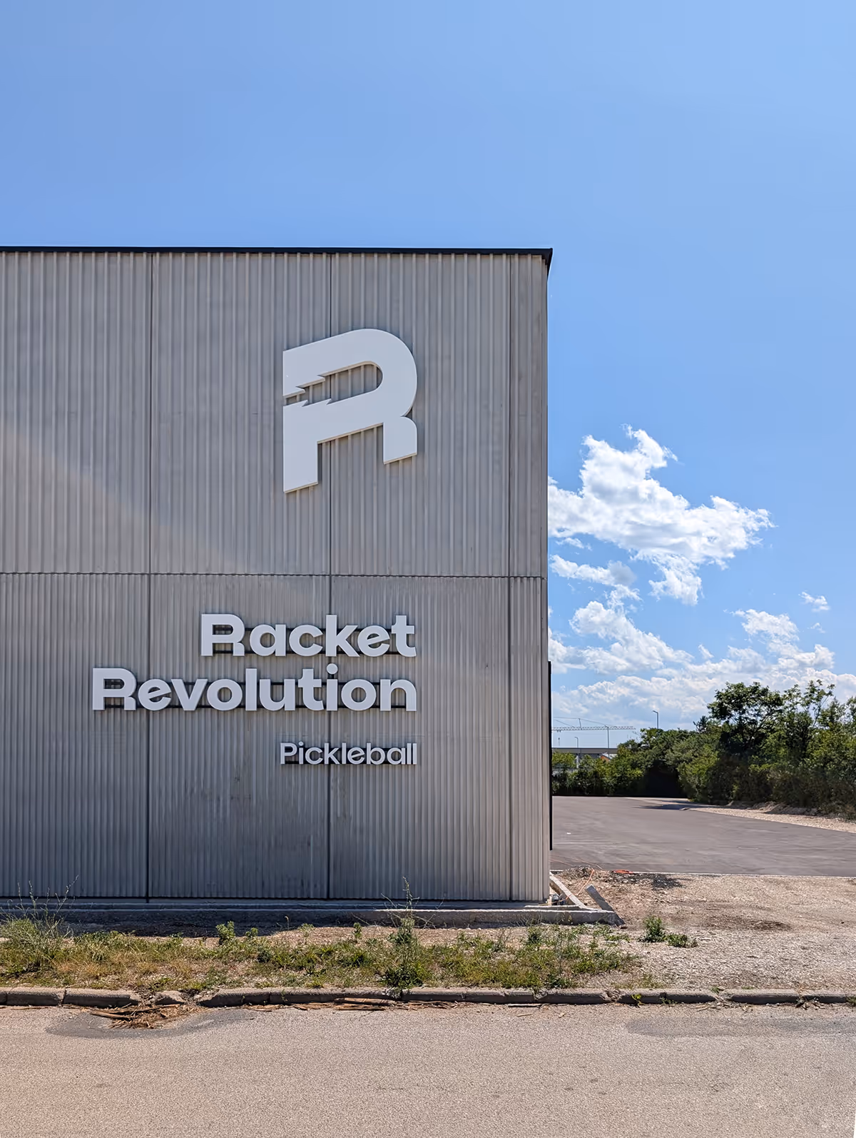 Racket Revolution Halle von außen, großer weißer Logo Schriftzug