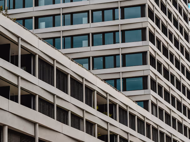 Modern office building exterior with rows of large glass windows and concrete structural elements.