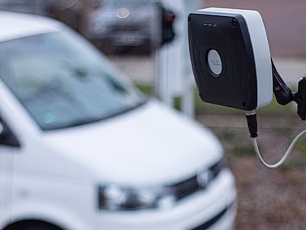 White electric vehicle connected to a black and white charging station on the right side.