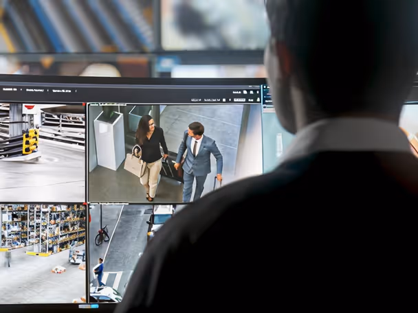 Security operator watching multiple CCTV camera feeds in a control room