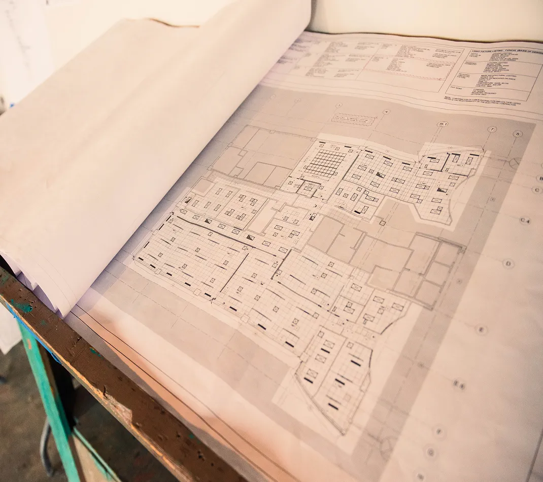 Rolled architectural blueprints with building floor plans laid out on a wooden table on an active job site.