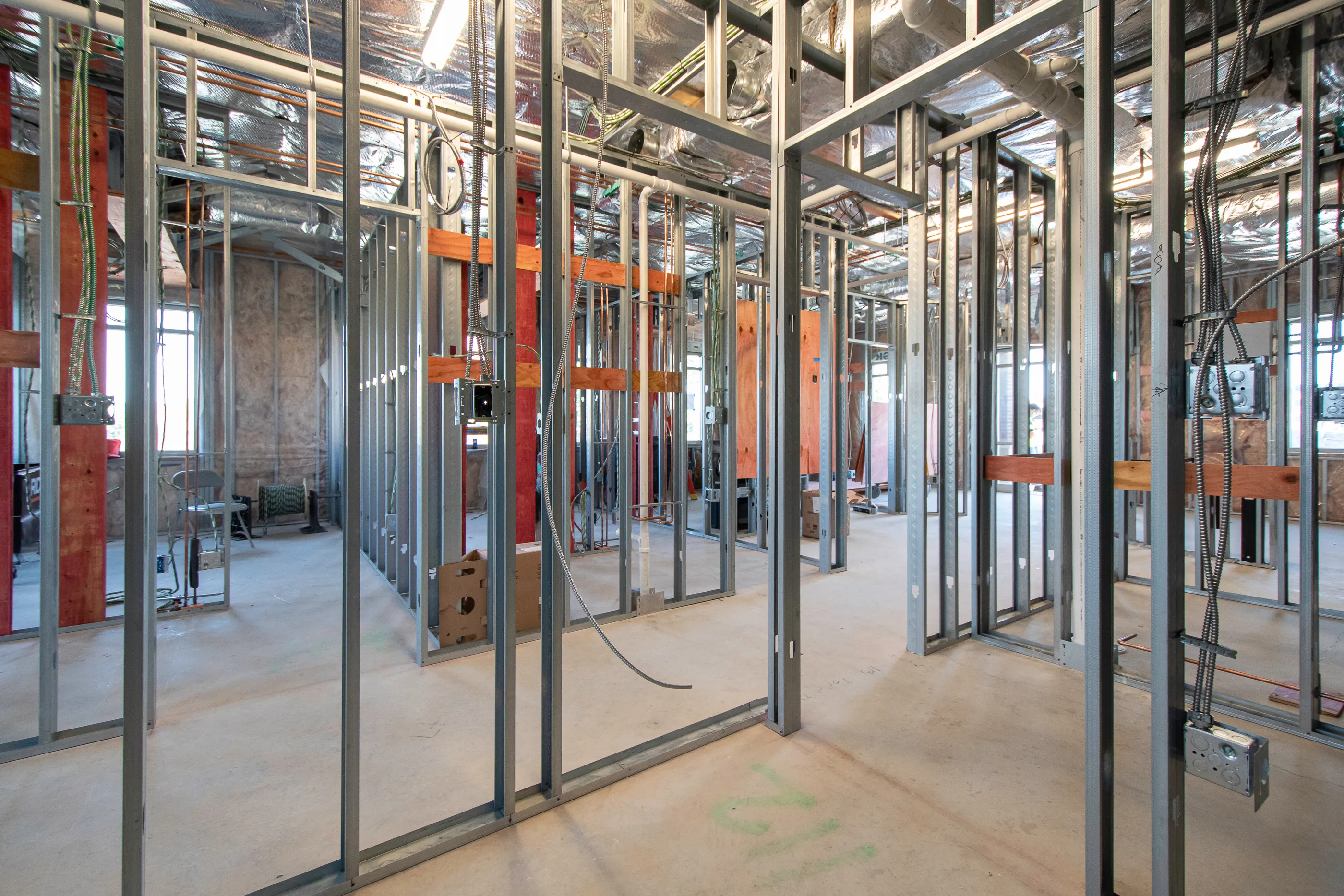 Interior of a Northern Kentucky building under construction with exposed metal framing, wiring, and insulated ceiling