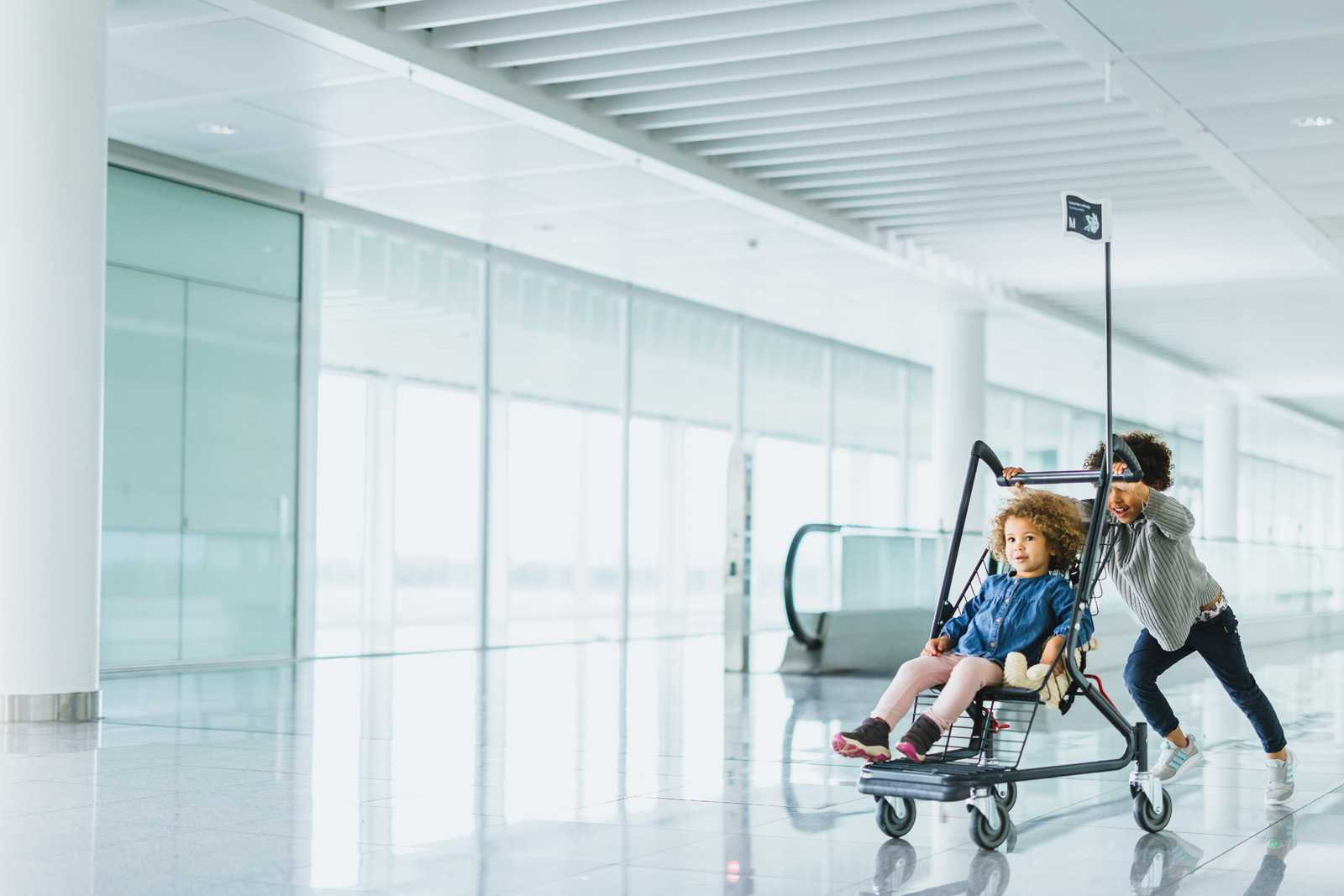 Markenfotografie: Familie mit Kinderwagen unterwegs im hellen Terminal des Flughafens München