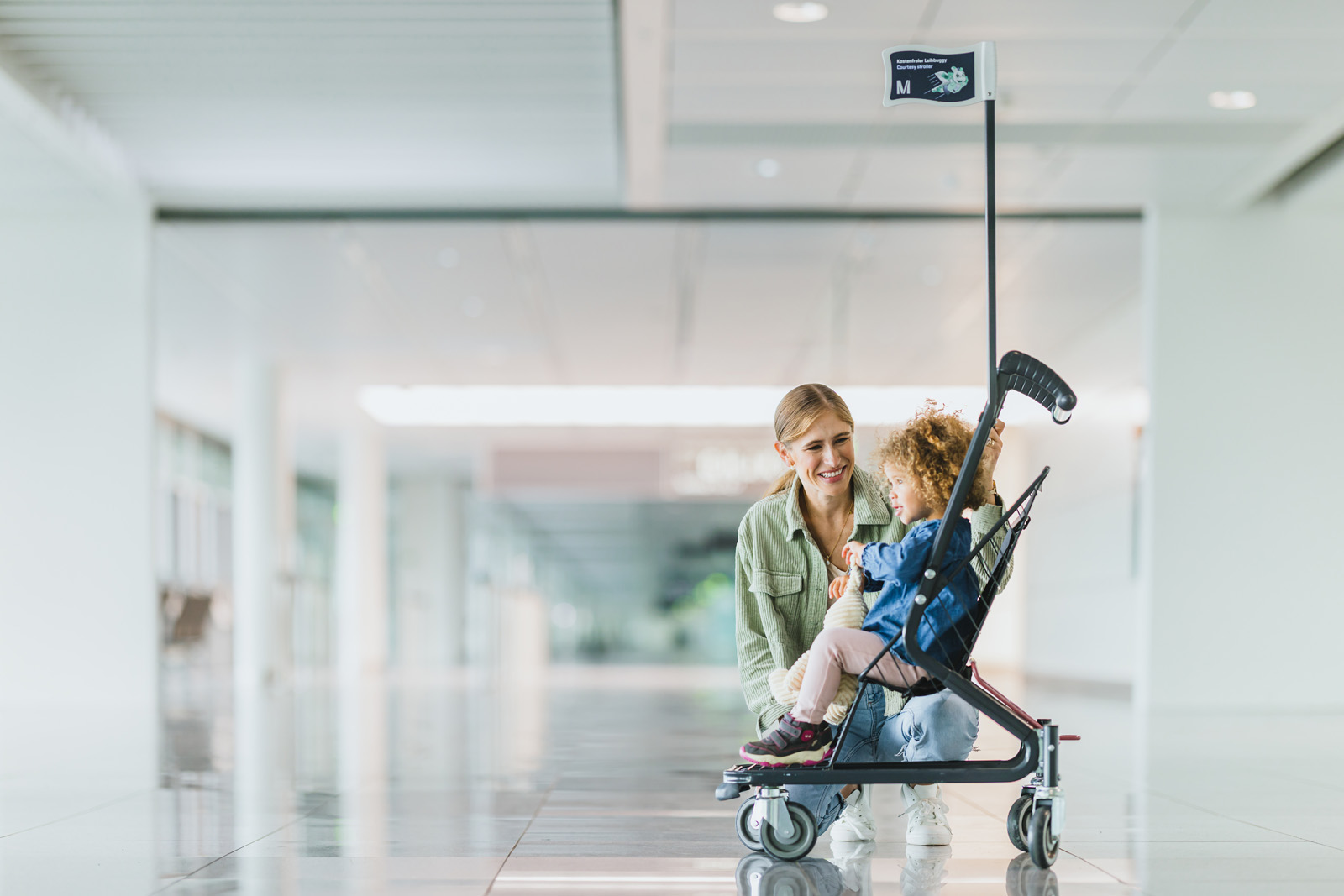 Markenfotografie: Mutter schiebt ihr Kind im Kinderwagen durch das Terminal des Flughafens München