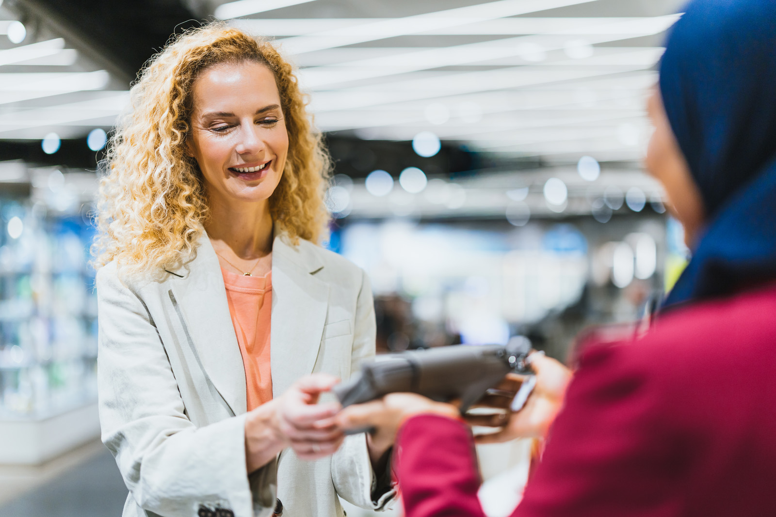 Markenfotografie: Kundin freut sich über ein Produkt in einem Shop am Flughafen München
