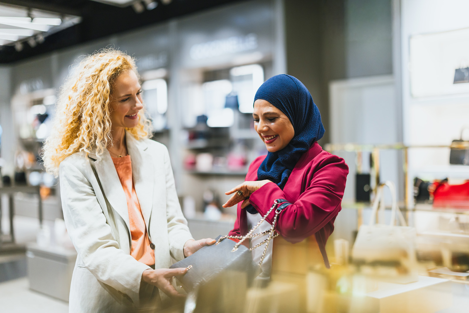 Markenfotografie: Verkäuferin überreicht einer Kundin ein Geschenkpaket in einem Shop am Flughafen München