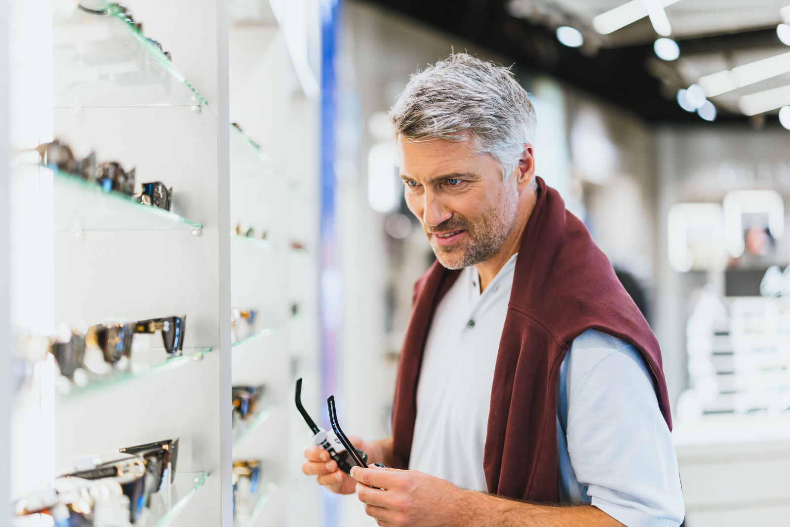Markenfotografie: Mann mit Brille stöbert in den Regalen eines Shops am Flughafen München