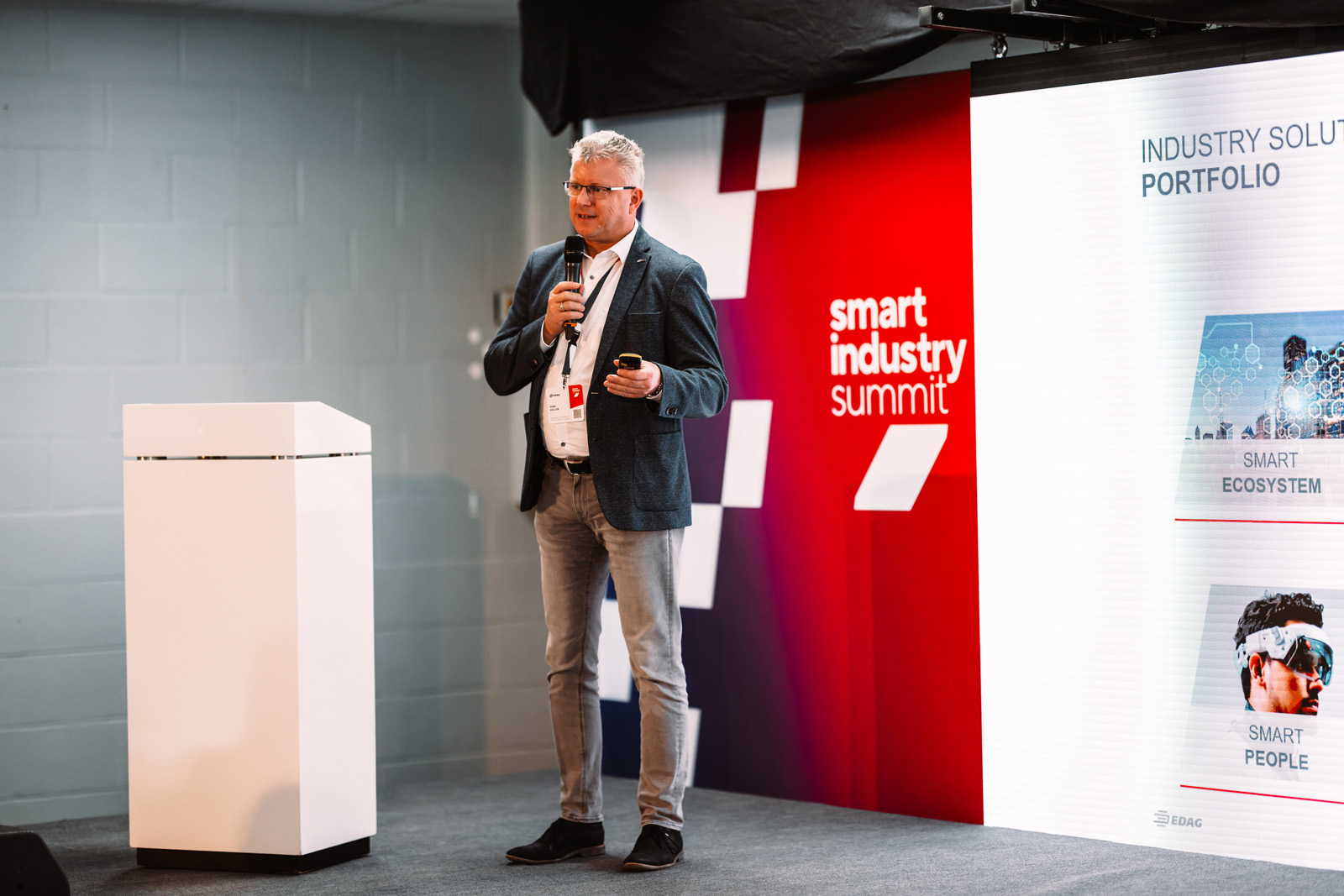 Eventfotografie: Redner auf der Bühne vor der Smart Industry Summit Wand von EDAG