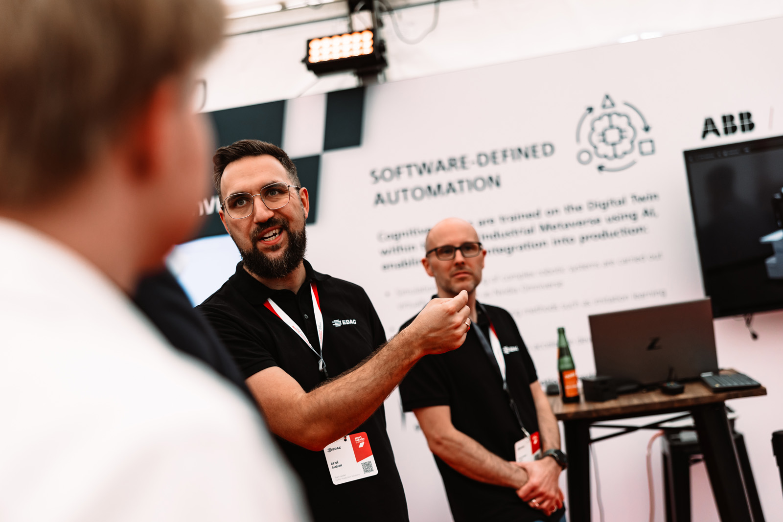 Eventfotografie: Besucher im Gespräch an einem Ausstellerstand zum Thema Automatisierung beim EDAG Summit