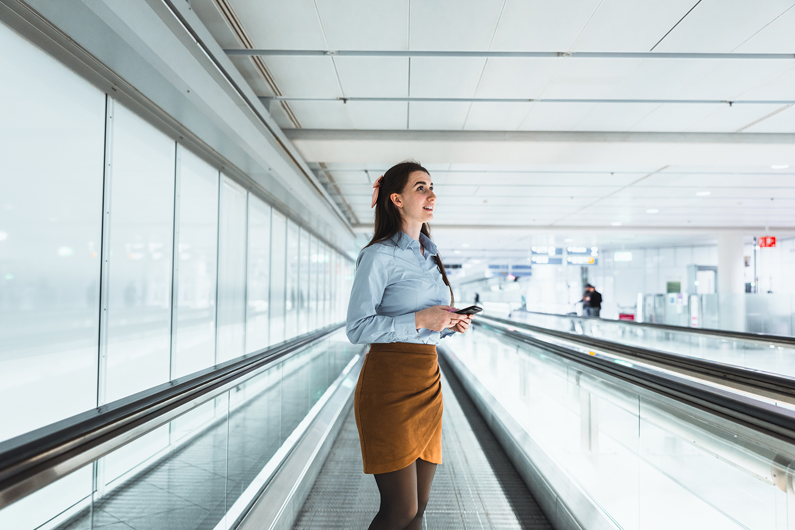 Mitarbeiterfotografie: Mitarbeiterin im Blazer auf dem Laufband im Terminal des Flughafens München