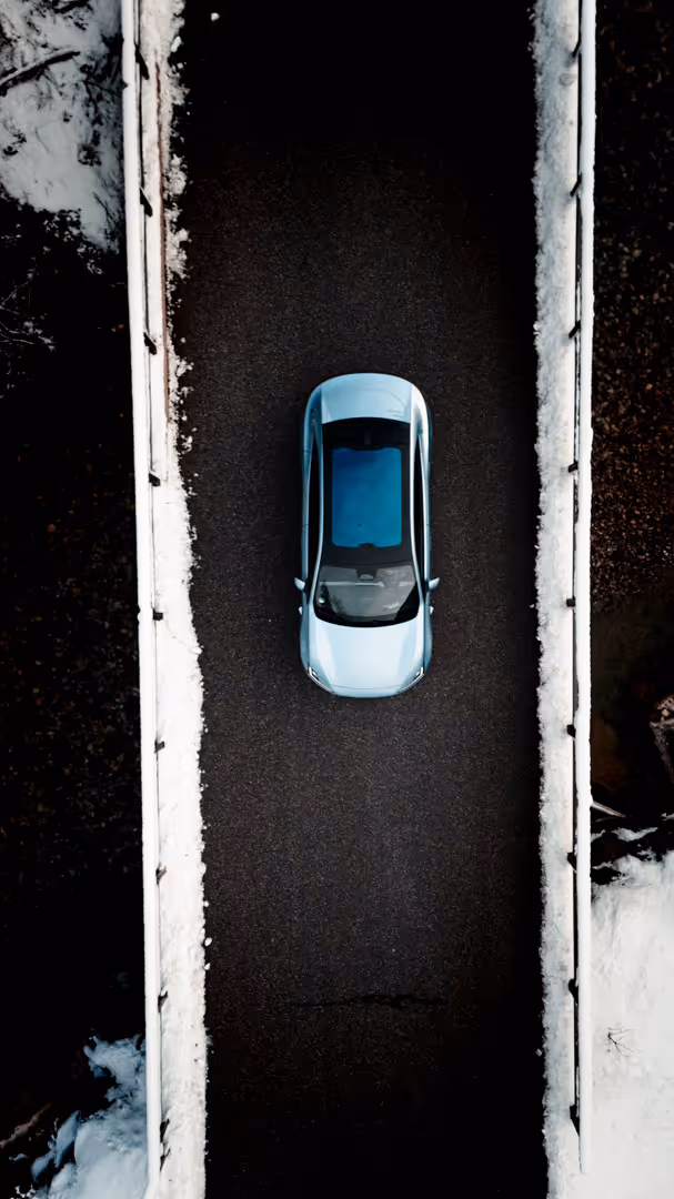 Automotive-Fotografie: Drohnenaufnahme von oben auf den Polestar zwischen verschneiten Bäumen