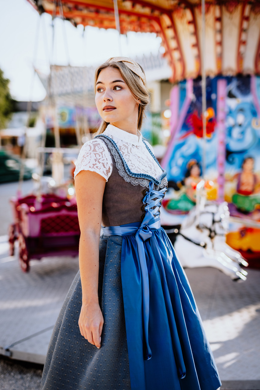 Modefotografie: Junge Frau in einem blauen Dirndl vor einem Kettenkarussel