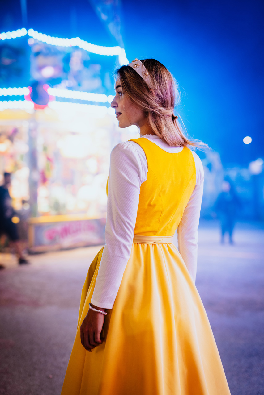 Modefotografie: Junge Frau in gelbem Dirndl bei Nacht