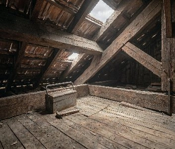 Combles non isolés d'un immeuble niçois surchauffés en été, plancher brûlant et air étouffant sous les tuiles.