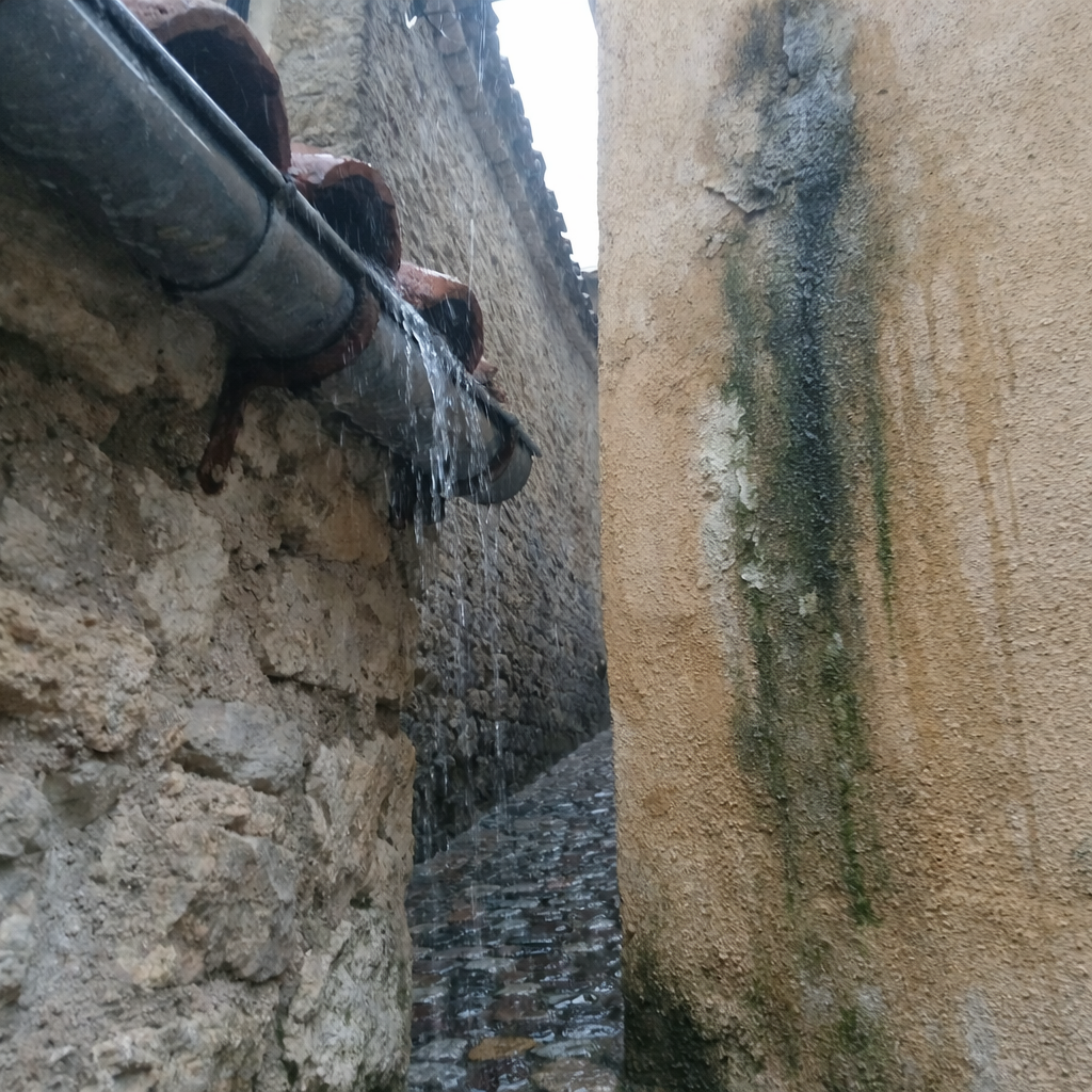 Chéneau saturé débordant sur la façade voisine dans une ruelle étroite du centre ancien d'Aspremont.