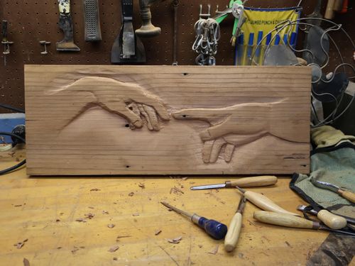 an image of a woodcarving that Eric made with handtools. the image is reminiscent of the hands in the painting "The Creation of Adam" on the roof of the Sistine Chapel. The hands are reaching out toward each other but not exactly touching signifying a striving for relationship.