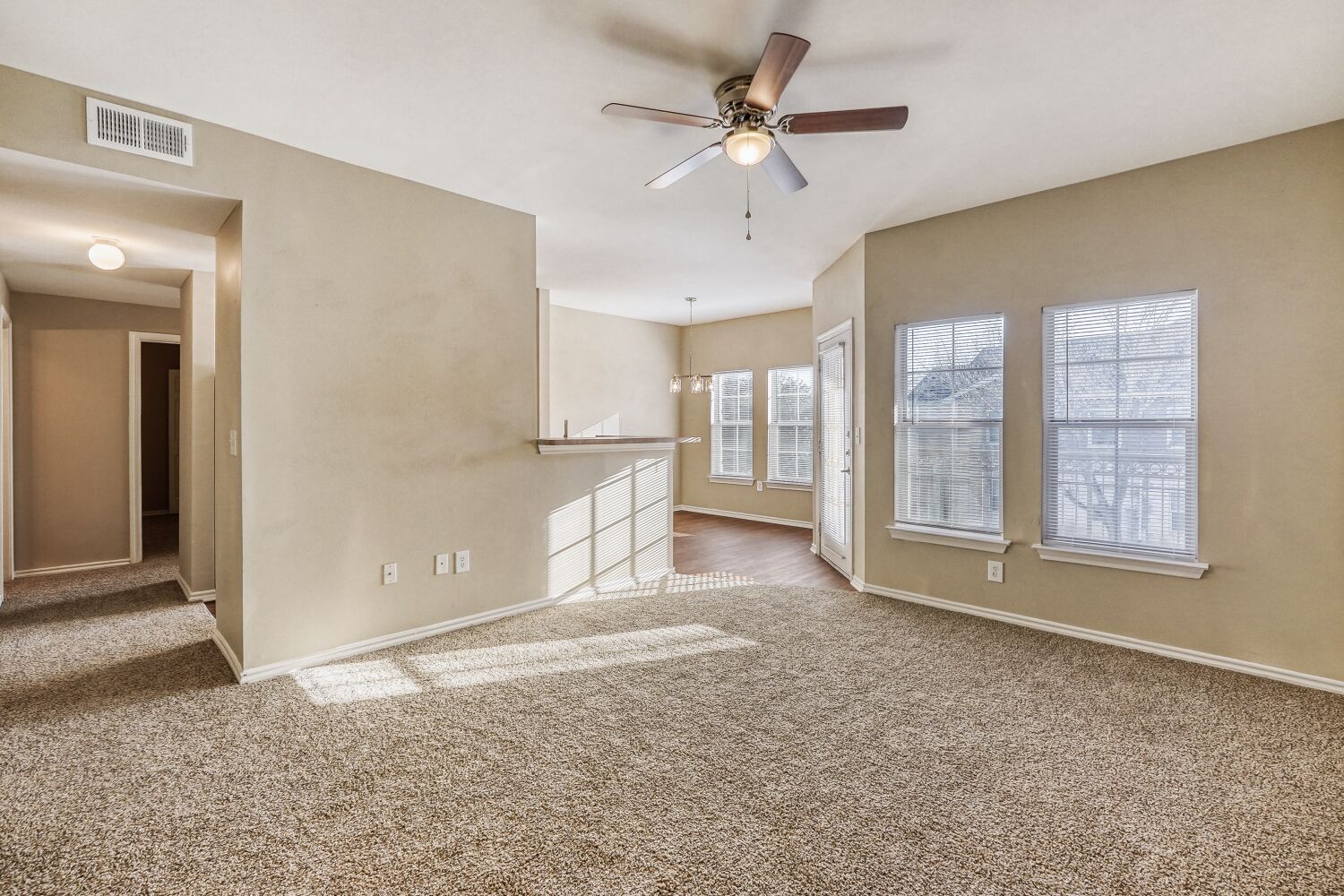 Living area unfurnished with ceiling fan and large windows