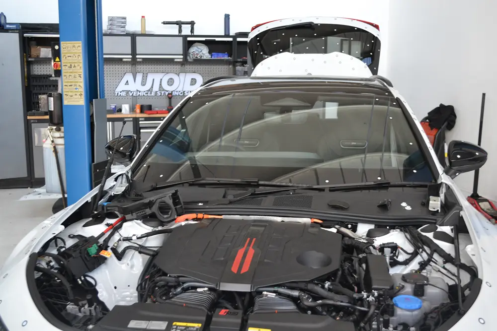 Car engine bay marked up for on-site 3D scanning in a workshop