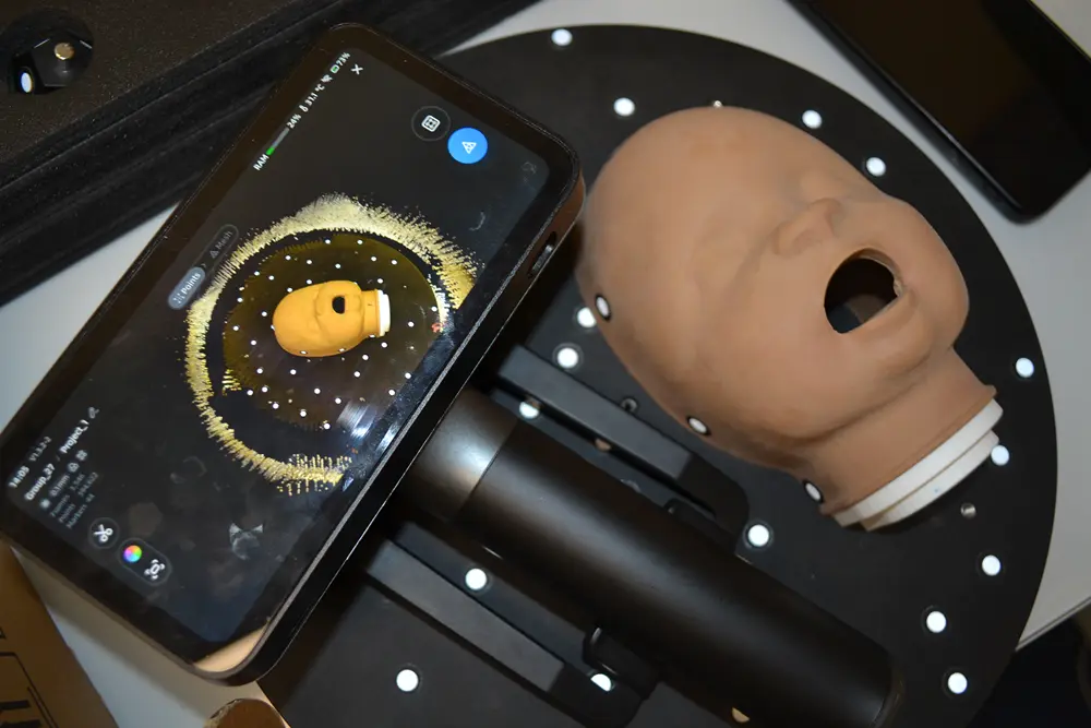 Handheld 3D scanner capturing a mannequin head on a marked turntable at Nexform