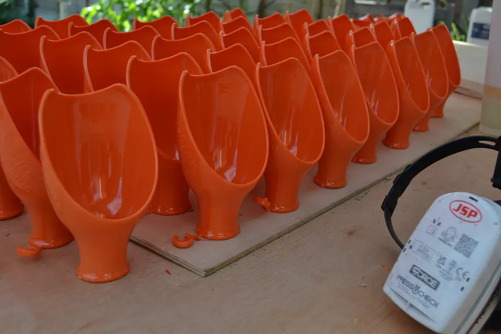 Rows of orange low volume manufactured parts lined up for finishing