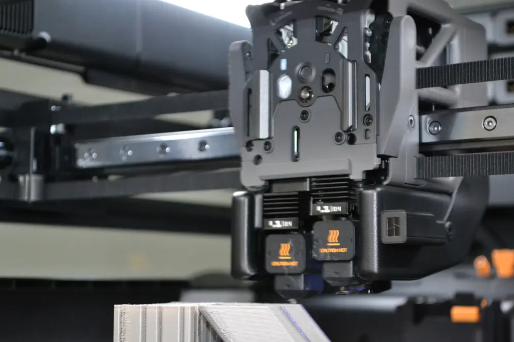 Close-up of a Nexform industrial FDM 3D printer toolhead mid-print