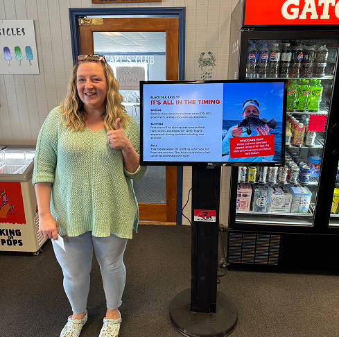 A proud business owner gives a thumbs up standing next to a WildCard screen