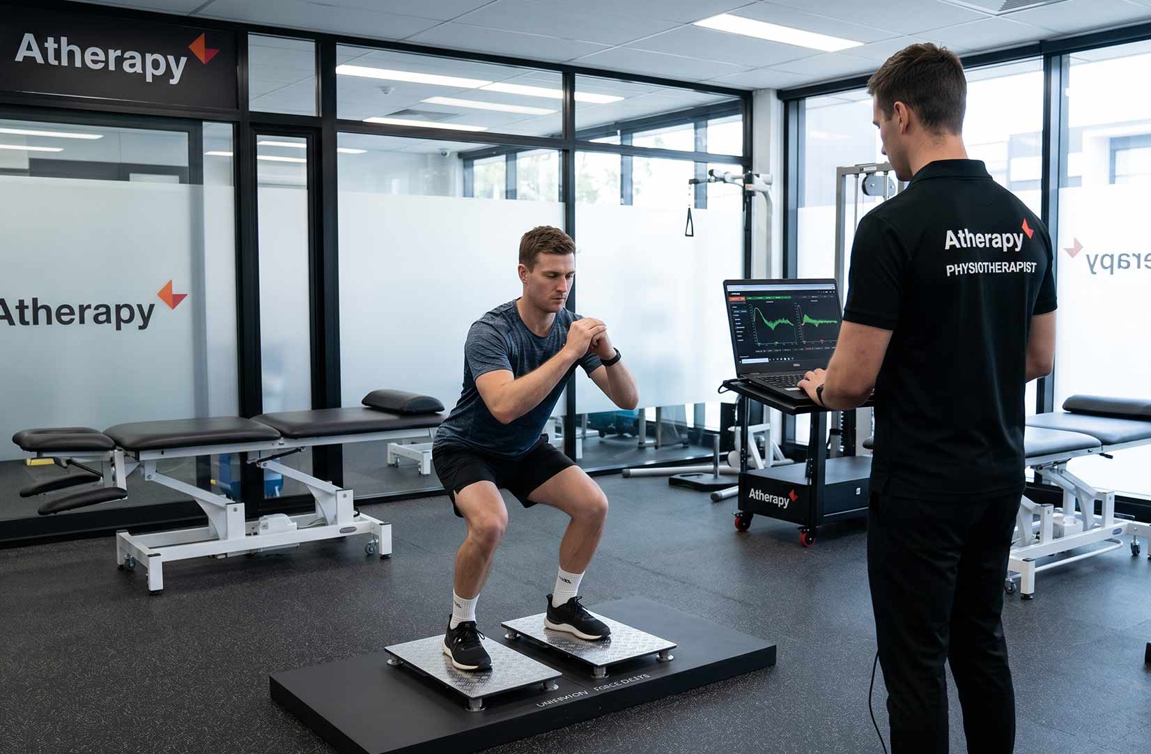 a man getting his knee tested on a force plate machine with a physio watching