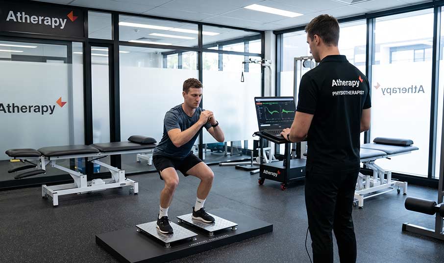 a man getting his knee tested on a force plate machine with a physio watching