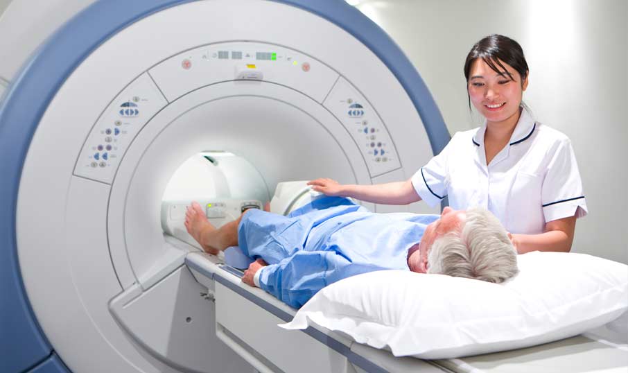 a patent going into an MRI scanning machine with a nurse stood next to him