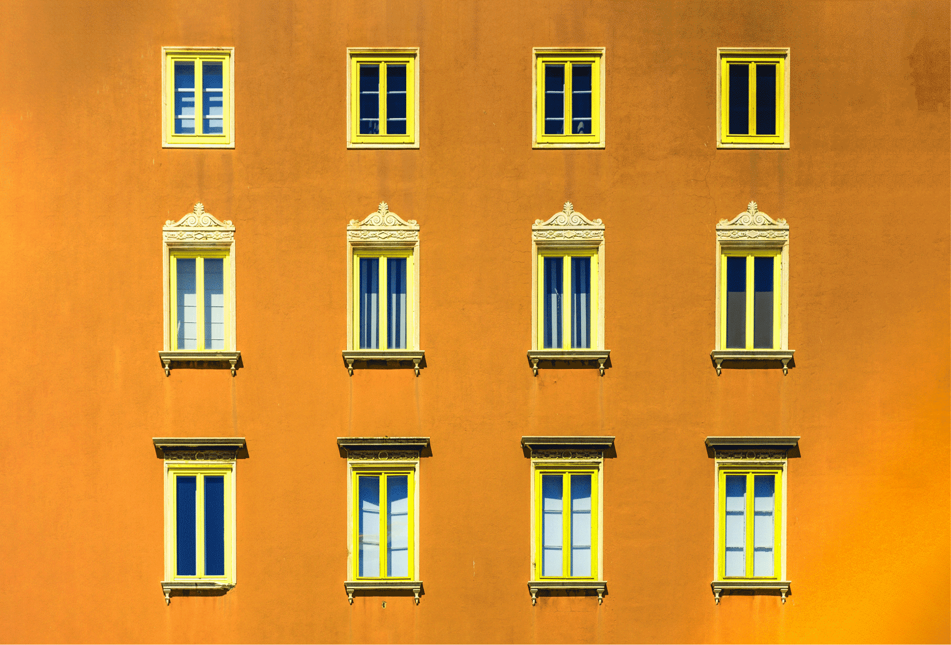 An orange wall lined with different types of windows