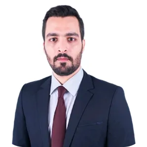 Man with short dark hair and beard wearing a dark suit, white shirt, and maroon tie against a white background.