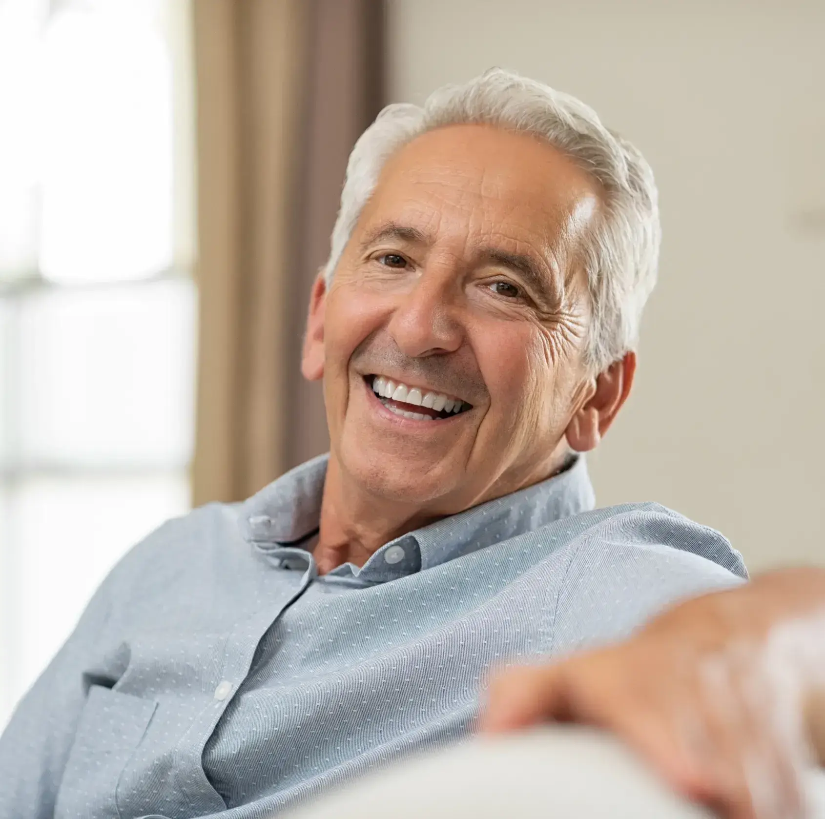 A man smiling while sitting on a couch.