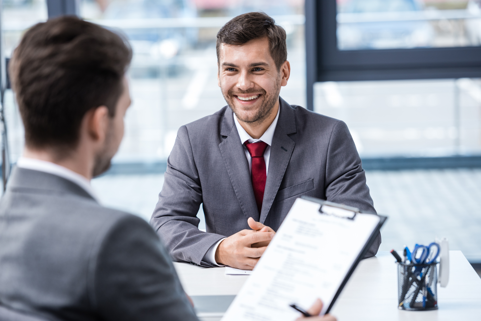 A man sitting at a desk talking to another man.