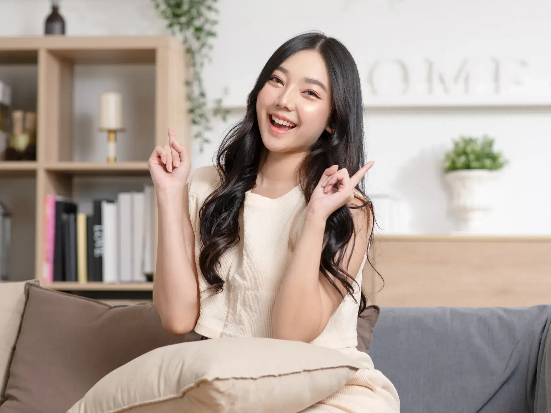 A woman sitting on top of a couch holding a peace sign.