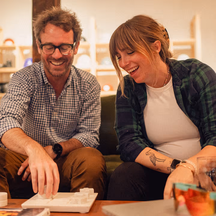A man and woman smiling and playing a tabletop game together indoors.