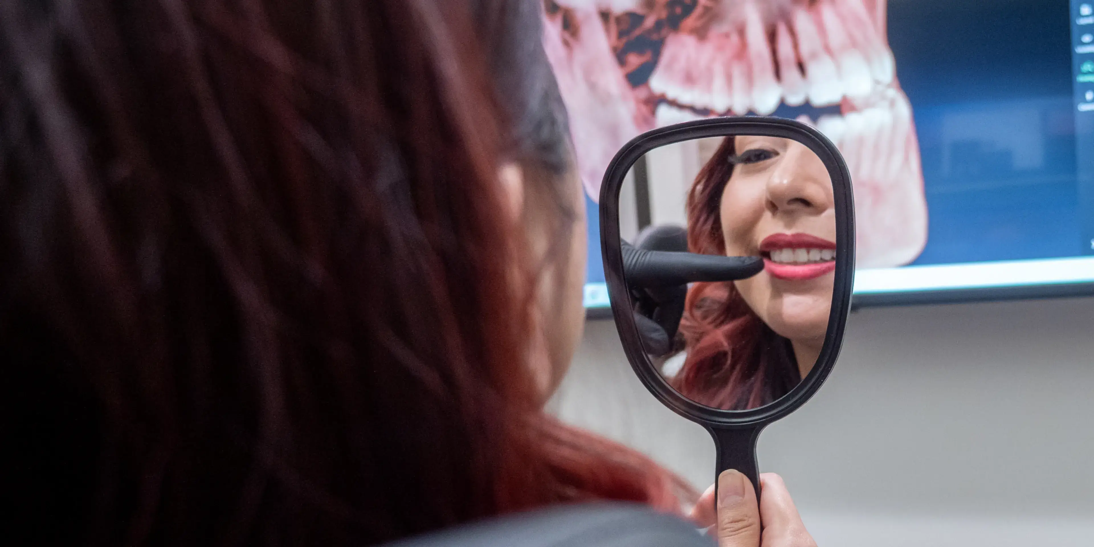 Two people in black shirts happily working together on a computer in an office.