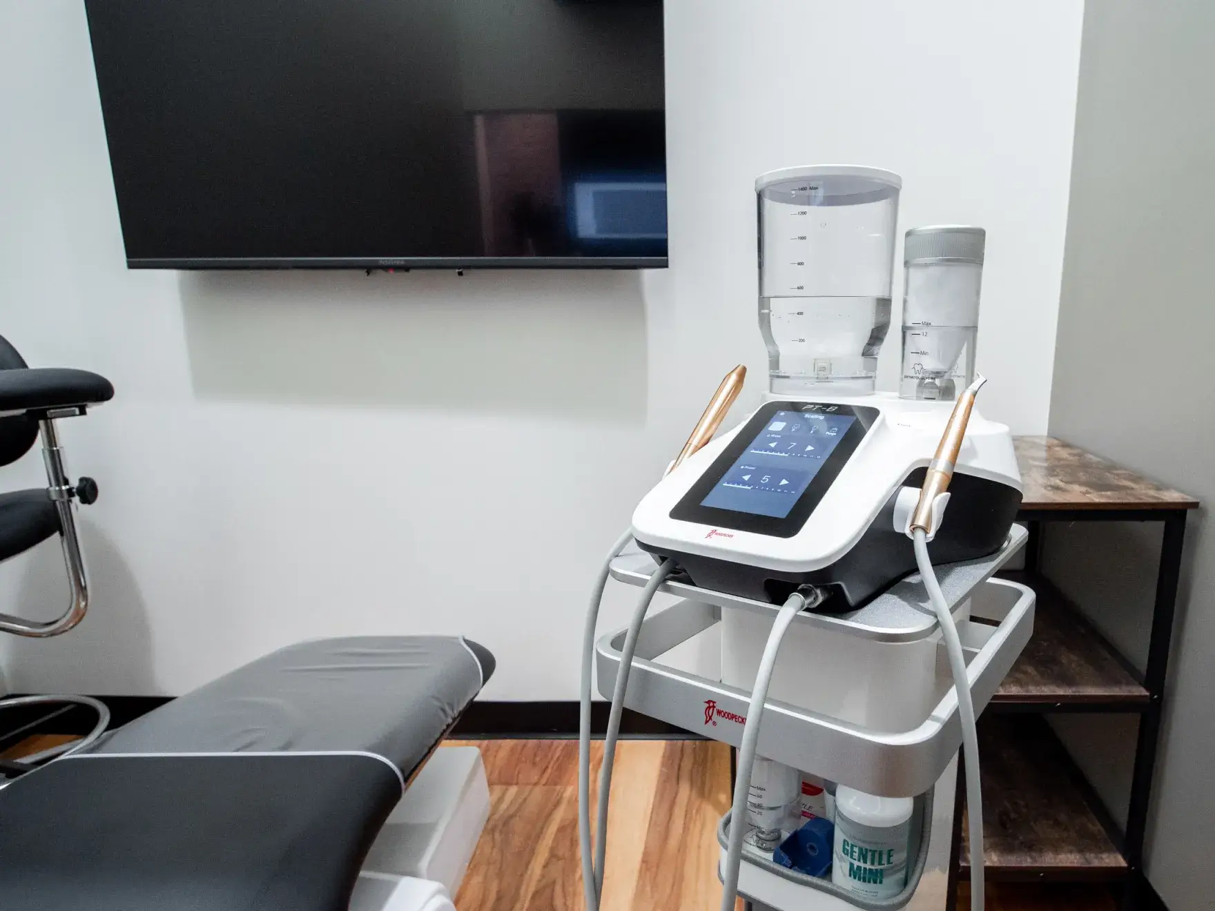 Two people in black scrubs stand and smile in front of a brick wall.
