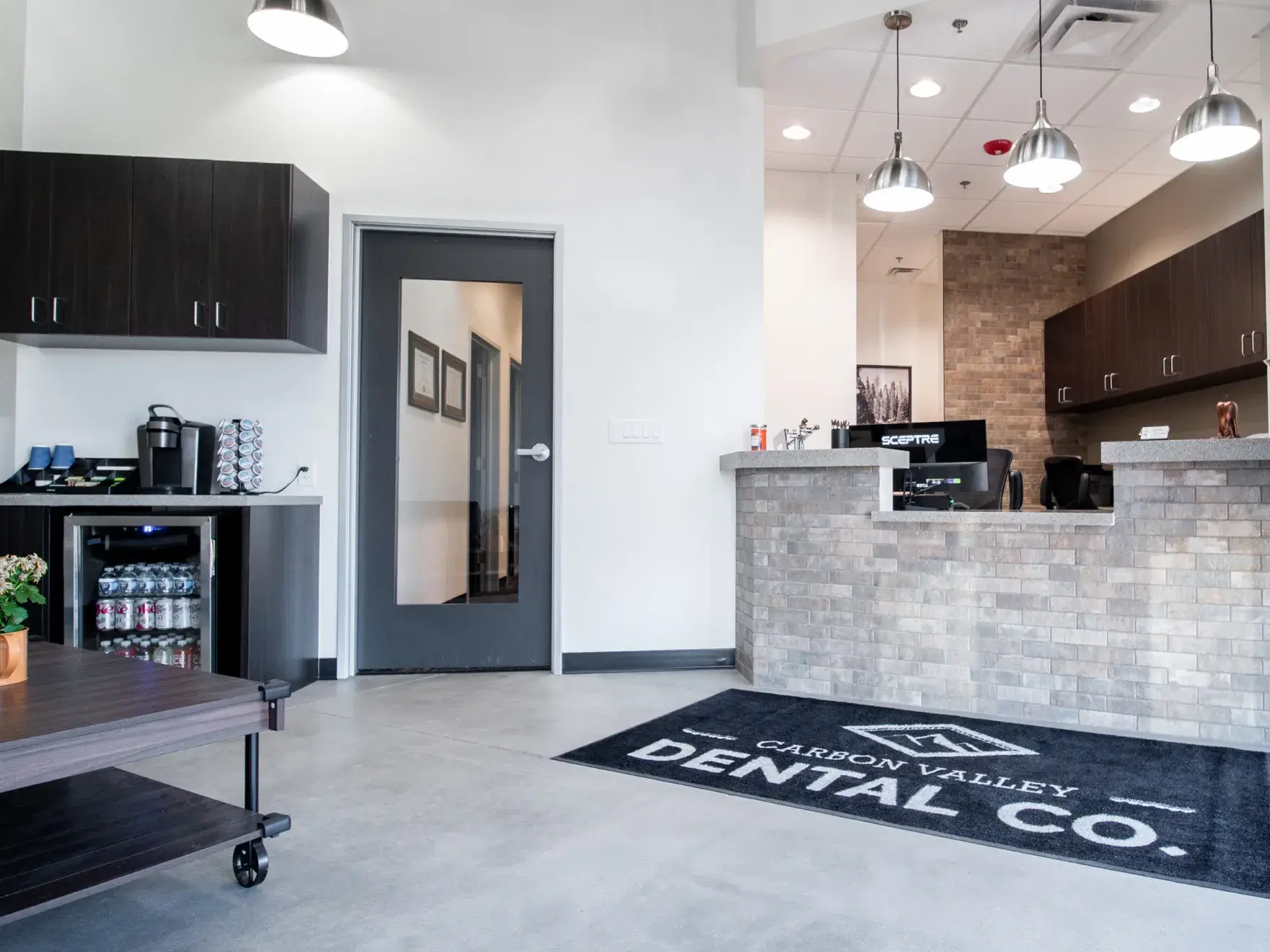 A woman sits in a chair holding a mirror while a man in scrubs smiles beside her.